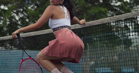 Sexy tennis player in a mini skirt sports wear on the court on a sunny day