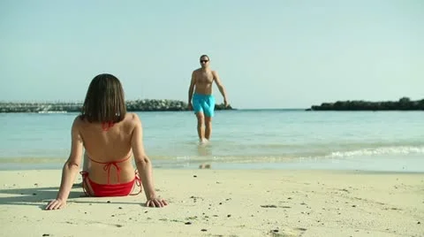 Sexy woman in bikini looking at man walking on the beach HD Stock Footage