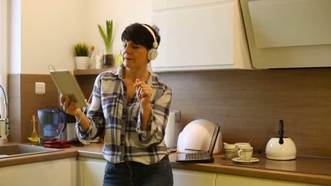 Sexy woman dancing in the kitchen while listening music on tablet Stock Footage 73314215