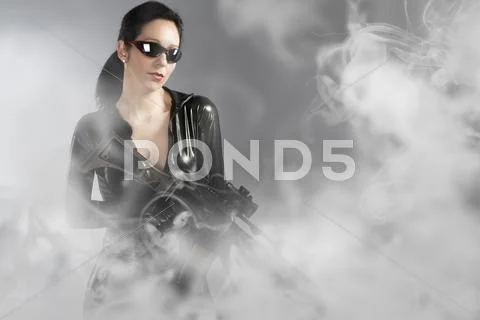 Sexy woman holding gun with helmet over smoke Stock Photos