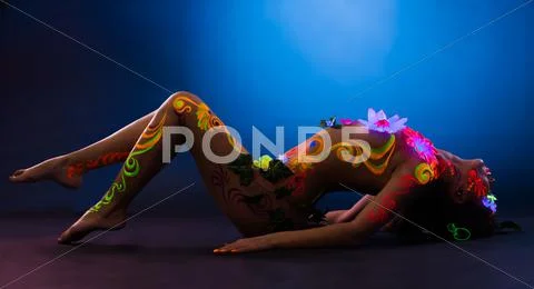 Sexy woman lay in glowing flowers and uv make-up Stock Photos