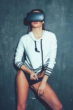 Sexy woman pulling pullover with VR glasses at wall Stock Photos