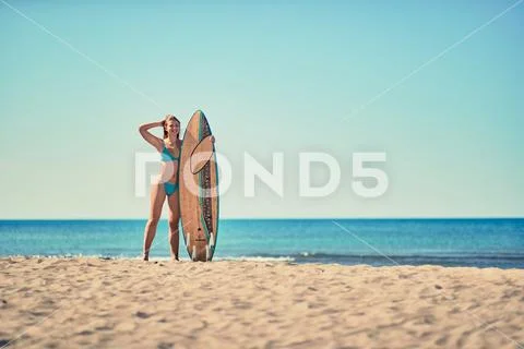Sexy woman surfers on a beach. Yong women holding a surfboard. Stock Photos