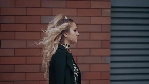 The sexy young blonde, in profile, walks fast and confidently forward, has long Stock Footage 157455053