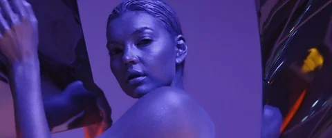 Sexy young model with braid tail posing in neon UV light looking at camera Stock Footage 125551096