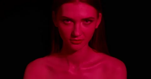 Sexy young woman with red lighting looks at the camera. Stock Footage 211683053
