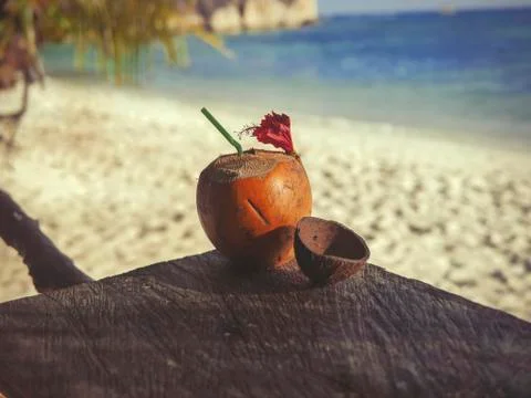 Seychelles coconut with a straw on a table in front of the ocean Stock Photos