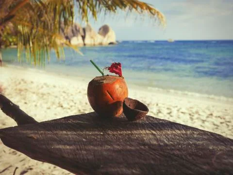 Seychelles coconut with a straw on a table in front of the ocean Stock Photos