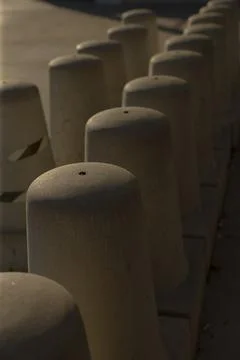 Shaded bollards create subtle patterns along quiet city streets at dusk Stock Photos