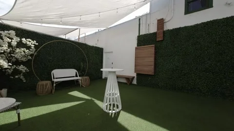 Shaded event patio with artificial grass and white cocktail tables Stock Footage 345562763