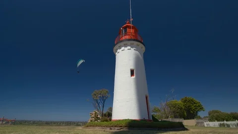 Shadow on 19th century lighthouse as paragliders fly close by. Stock Footage 93100144