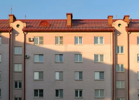 Shadow and sunny evening light on facade of pink brick apartment building Stock-Fotos