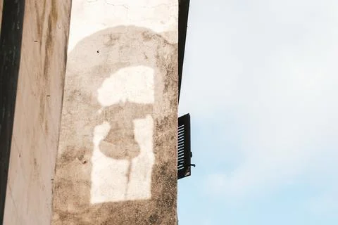 Shadow of bell on weathered wall with open shutter Fotos de archivo