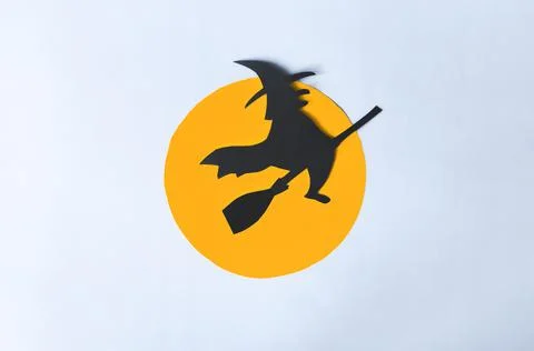 The shadow of a black ghost in a hat on a broomstick against the background. Stock Photos