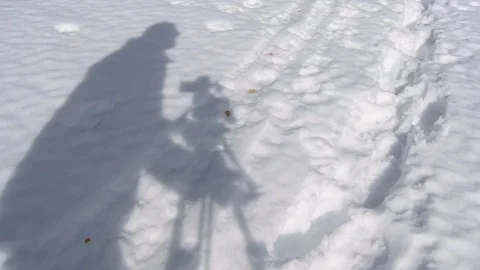 Shadow of a cameraman on the snow while recording in a day Stock Footage 83404990