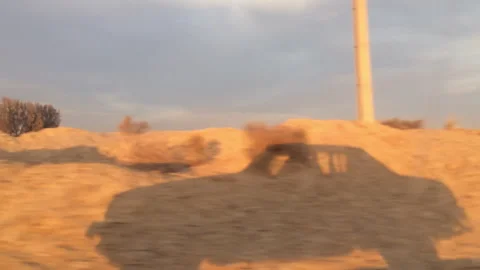 Shadow of a car moving across a dusty desert landscape Stock Footage 343575695