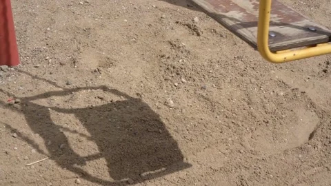 Shadow cast by swing moves on sand following teeterboard Video stock 134999057