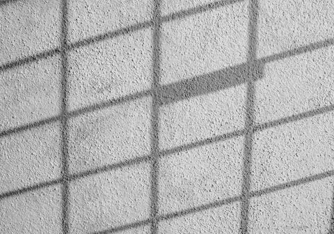 Shadow of a check pattern steel grill over a wall Stock Photos
