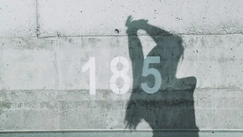 Shadow on the concrete wall of the long-haired woman stretching. Morning sports Stock Footage 158810910