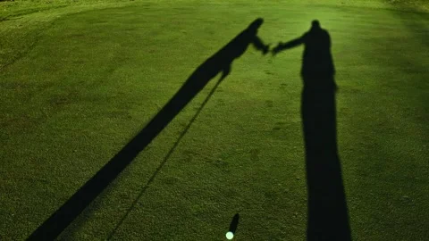 Shadow of a Couple of Golfer Shaking Hands on the Putting Green and a Golf Ball Stock Footage 265058489