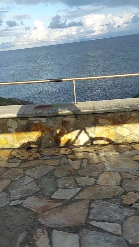 Shadow of Cyclist Riding Along Coastal Promenade with Ocean View Видео 342938518