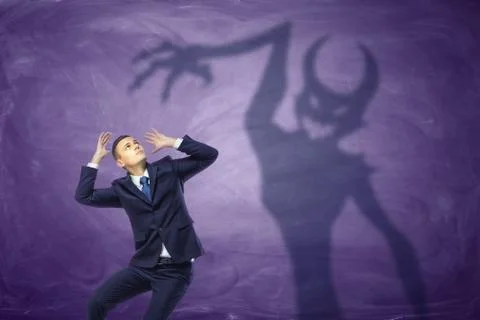 Shadow of devil trying to catch the frightened businessman 스톡 사진