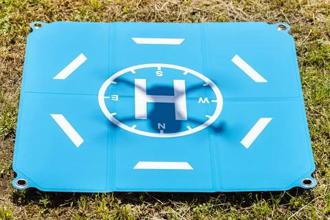 The shadow of the drone taking off is visible on the blue landing pad lying o Stock Photos