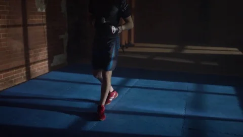Shadow of fighter with boxing gloves near brick wall . Young man is standing Stock Footage