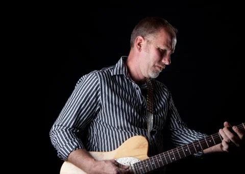 Shadow filled shot of a rugged looking guitar player Stock Photos