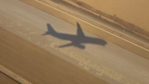 The shadow of flying plane on the ground on a sunny day. View from plane window. 库存影片 331556677