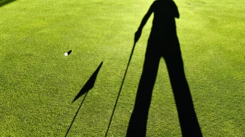 Shadow of a Golfer and a Flag on the Putting Green and a Golf Ball Rolling 動画素材 272762452