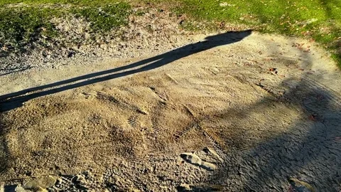 Shadow of a Golfer Hitting with His Golf Club the Golf Ball in the Sand Trap Видео 265216759
