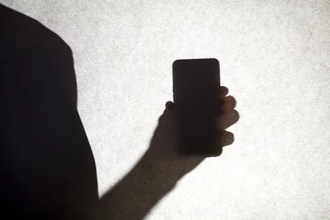 The shadow of a guy holding a smartphone. Stock Photos