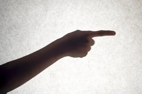 The shadow of a hand with an outstretched finger points to the side. Stock Photos