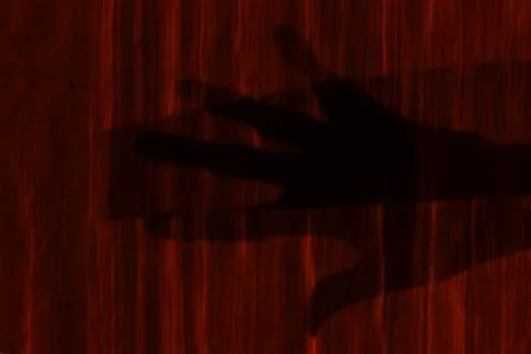 A shadow from a hand on a red wall. Light from a street lamp on the street. Stock-Fotos