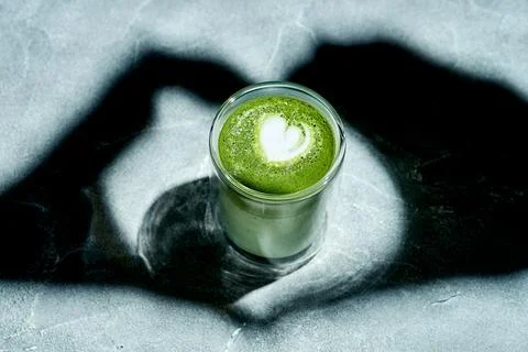 Shadow of hands making heart on matcha latte background. Foto stock