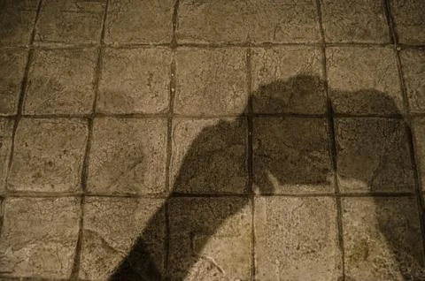 Shadow the hands of a man holding a camera on the concrete floor of an urban  Stock Photos