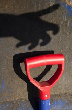 Shadow image of a hand tries to grasp red shovel handle, Finland Photos