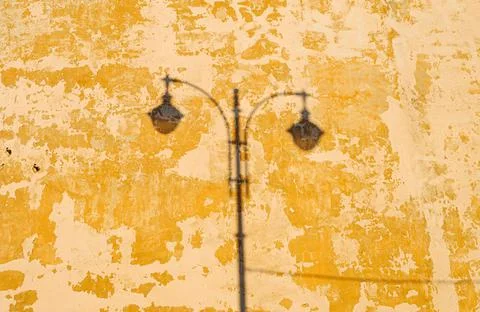 Shadow of a lantern on an old yellow wall Stock Photos