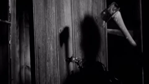 Shadow of man about to break down wooden door with axe Stock Footage 260257144