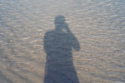 The shadow of a man alone on the water. Stock Photos