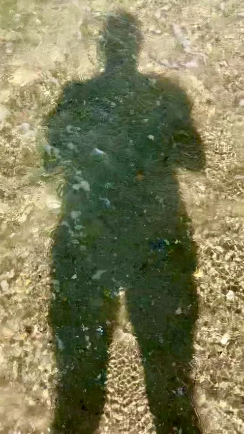 The shadow of a man at the bottom with pebbles is washed by sea water Stock Footage 140449534