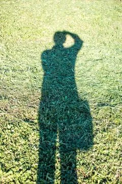 Shadow of a man with a camera against the background of mown green grass Фото