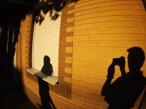The shadow of a man with a camera on the illuminated wall Stock Photos