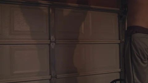 Shadow of a man doing pullups on a garage door in 4k. Stock Footage 93612734