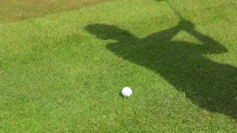 The shadow of the man on a golf course hits the ball with a club Stockbeeldmateriaal 169907878