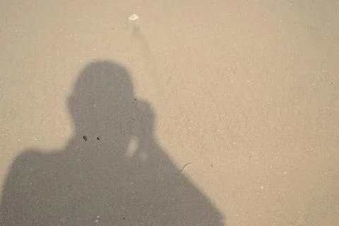 Shadow of a man on a light brown beach sand Stock Photos