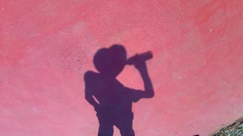 The shadow of a man in a Panama hat drinking from a bottle Vídeo Stock 342286656