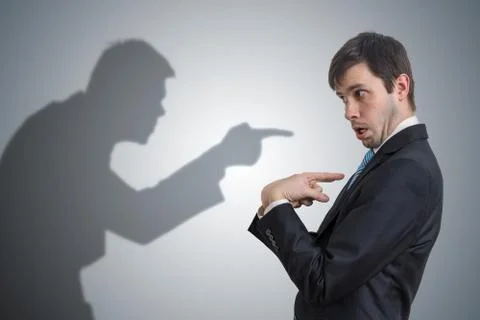 Shadow of man is pointing and blaming businessman. Conscience concept. 스톡 사진