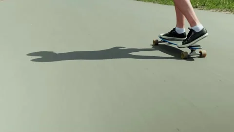 Shadow of a man skateboarding along an empty road and pushing off with his foot Stock Footage 133060135